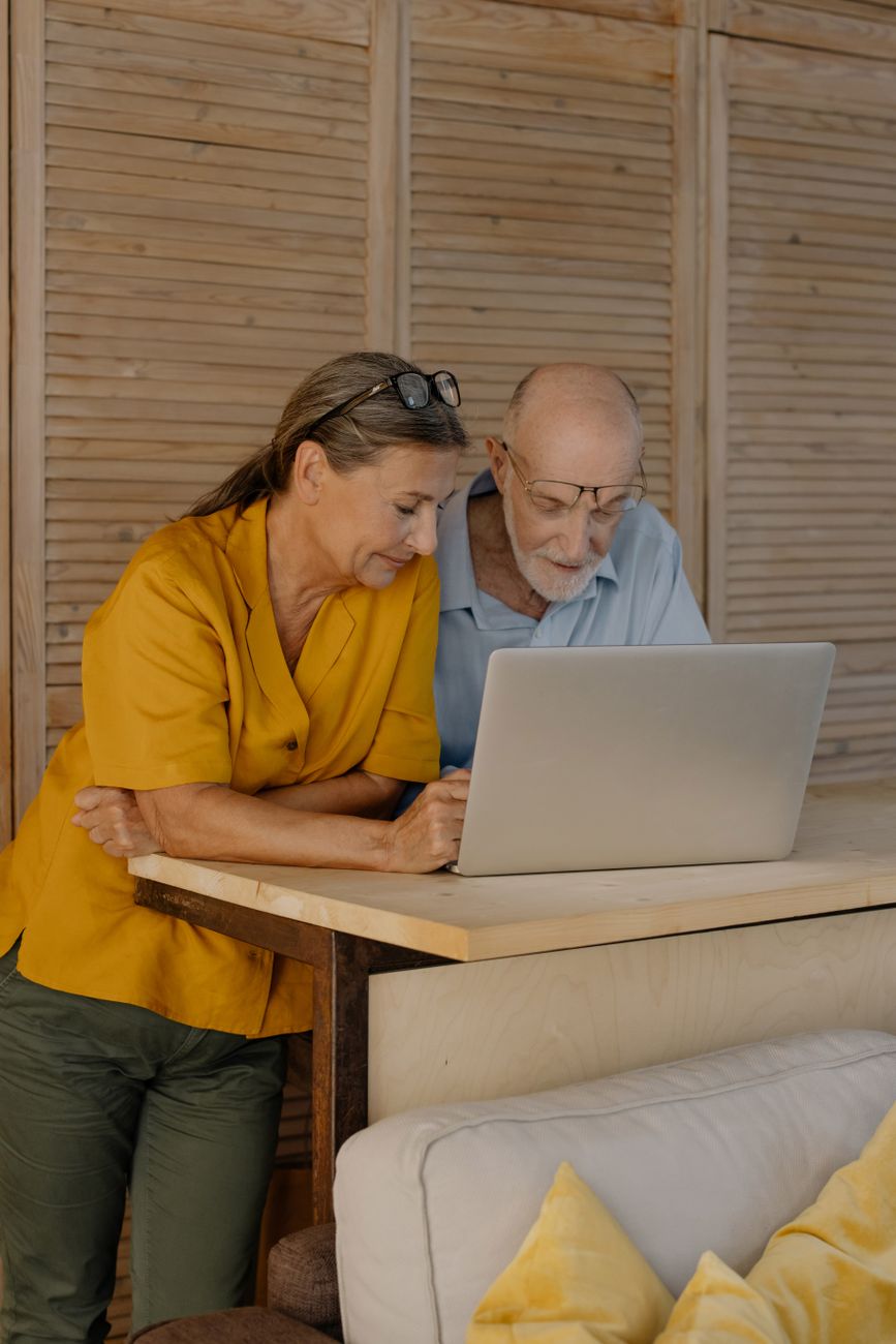 an elderly couple looking at a laptop